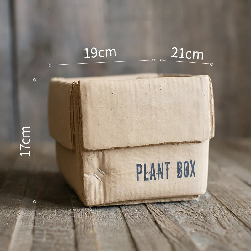 Cement flower pot with brown paper box texture and drainage holes, shown in a neutral home setting.