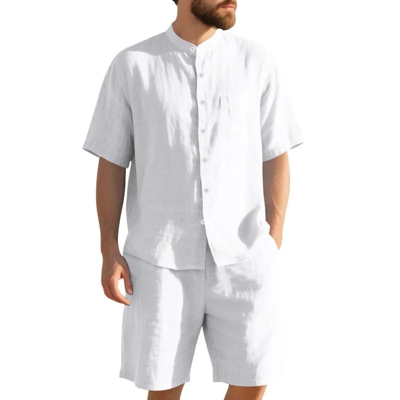 Man wearing a light blue linen blend Henry collar short sleeve suit top with matching shorts.