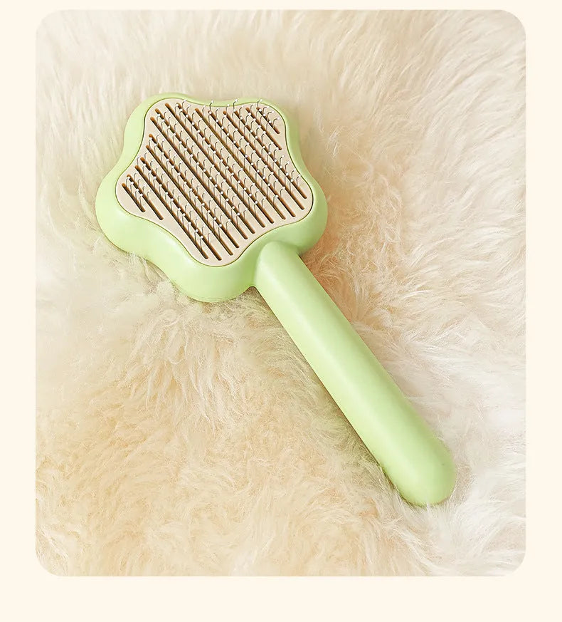 Green self-cleaning stainless steel pet comb with removable needle head on a white background.