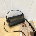Vegetable-tanned leather cylindrical crossbody phone bag in black colour showing adjustable strap and visible stitching