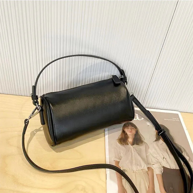 Vegetable-tanned leather cylindrical crossbody phone bag in black colour showing adjustable strap and visible stitching