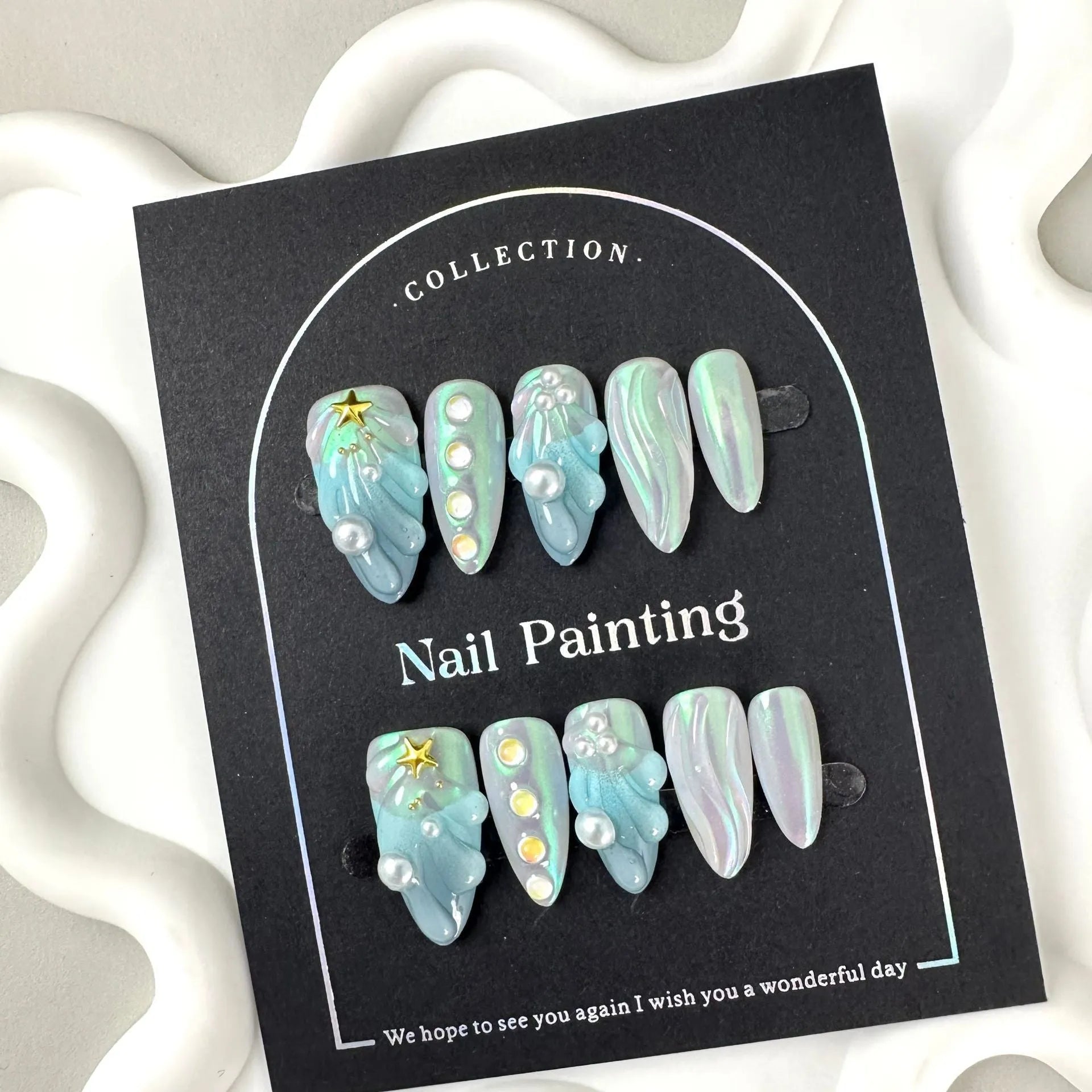 Blue plastic artificial nail tips set on a card, showing sizes labelled XS, S, M, and L.