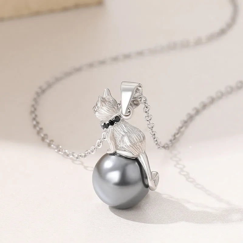Close-up of a sterling silver cat pendant on a clavicle necklace chain.