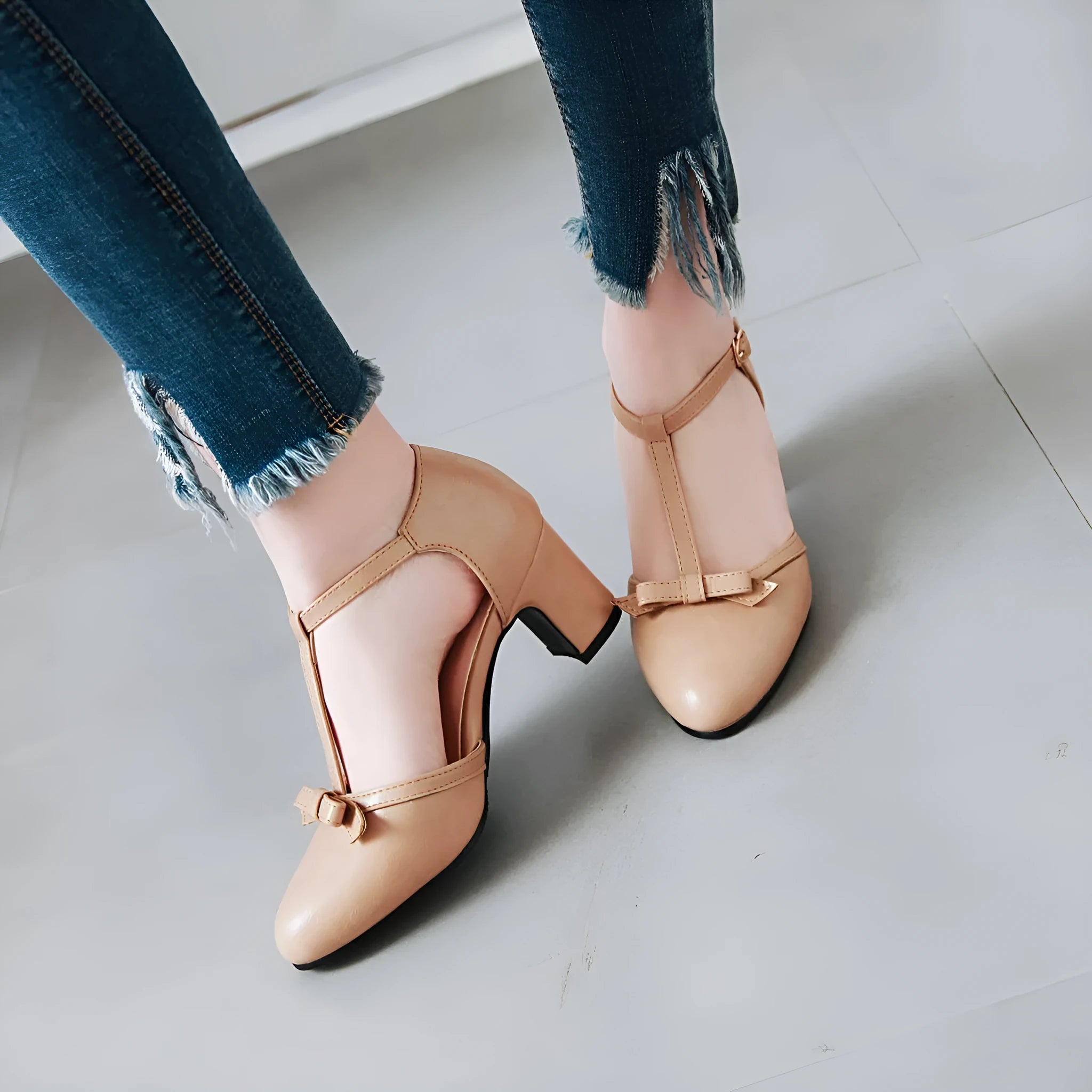 Women's apricot chunky heel sandals with a hollow-out round toe, T-strap buckle, and a black bow detail.