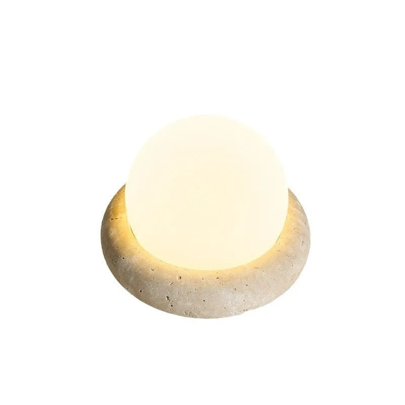 Cream-coloured round bedside night lamp with remote control on wooden table