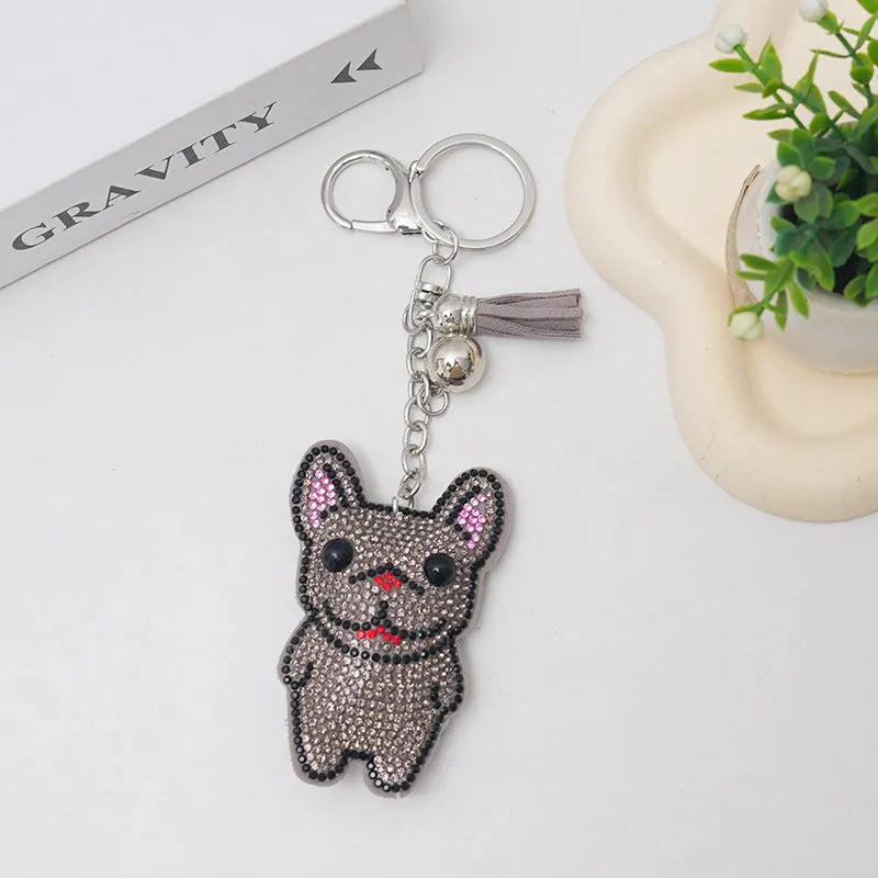 Close-up of a French dog style cartoon bear rhinestone keychain charm on a keyring.