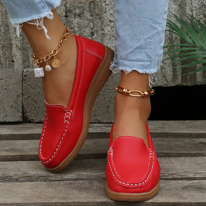 Women's flat slip-on loafers in PU leather, showing colour options and round toe design with decorative stitching.