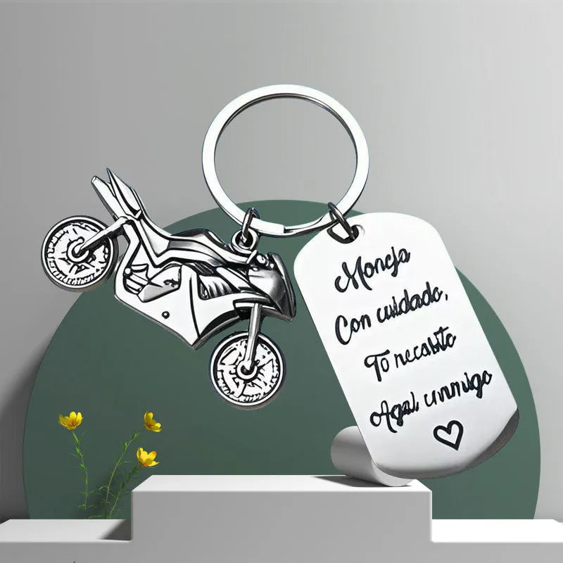 Close-up of a metal motorcycle-themed inspirational keychain next to a red flannel storage bag