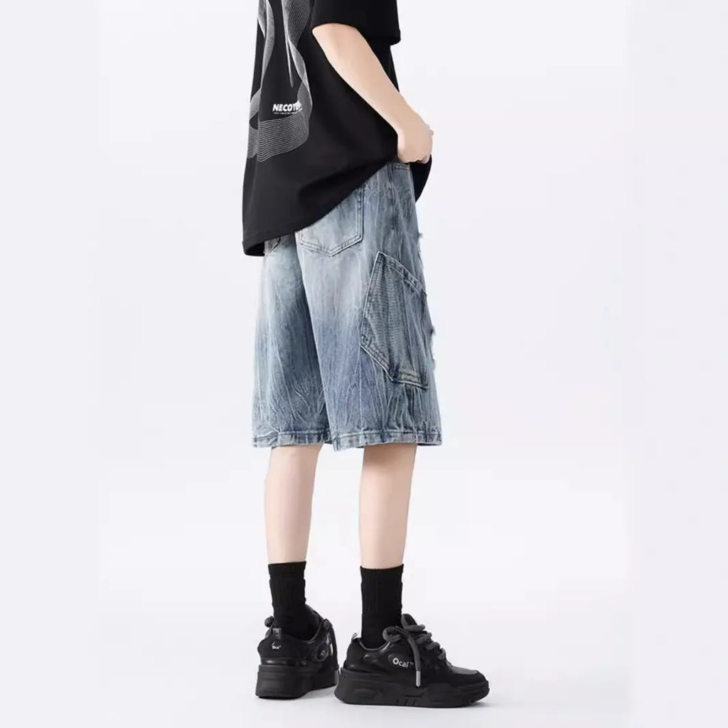 Model wearing loose-fit washed denim shorts with ripped details in blue.