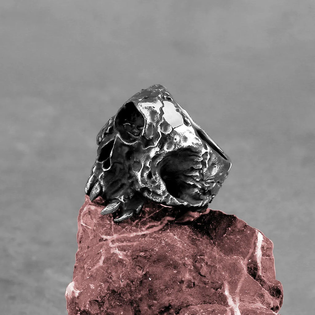Close-up of a retro alloy ring with a detailed one-eyed skull design on a dark background.