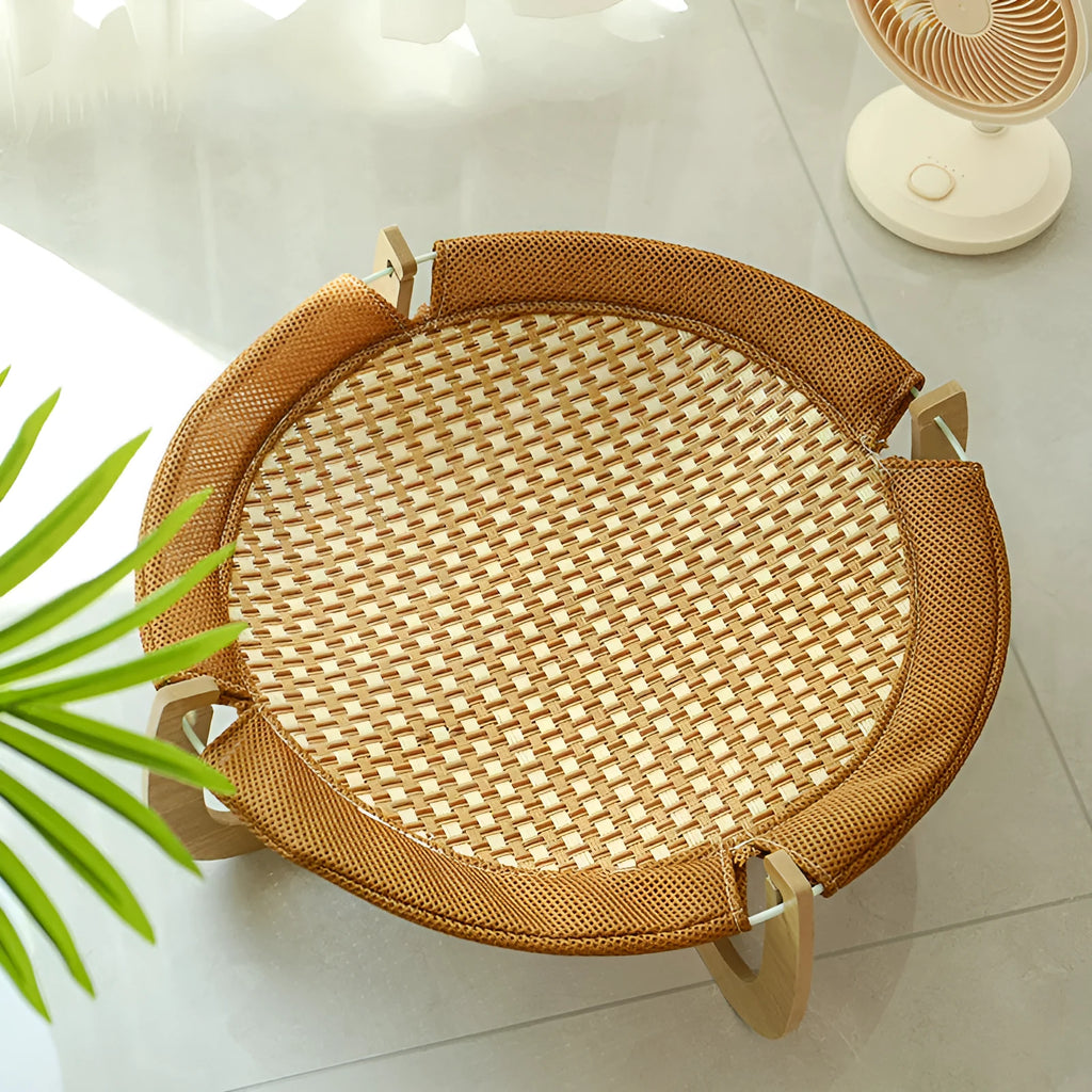 Natural brown woven rattan pet hammock with raised sides on a wooden floor.