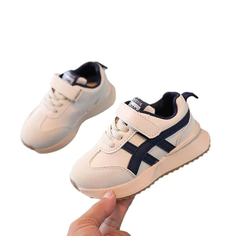 Children's white synthetic leather sneaker with Velcro strap and non-slip rubber sole.