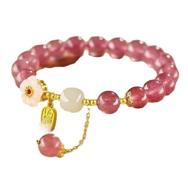 Handmade strawberry quartz crystal bracelet with Hetian jade peach blossom charm on a wrist.