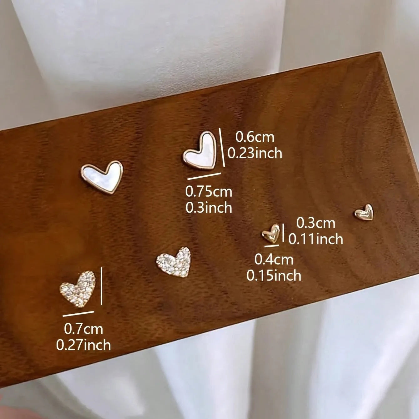 Three pairs of heart-shaped alloy earrings in gold, black, and pink with electroplated finish