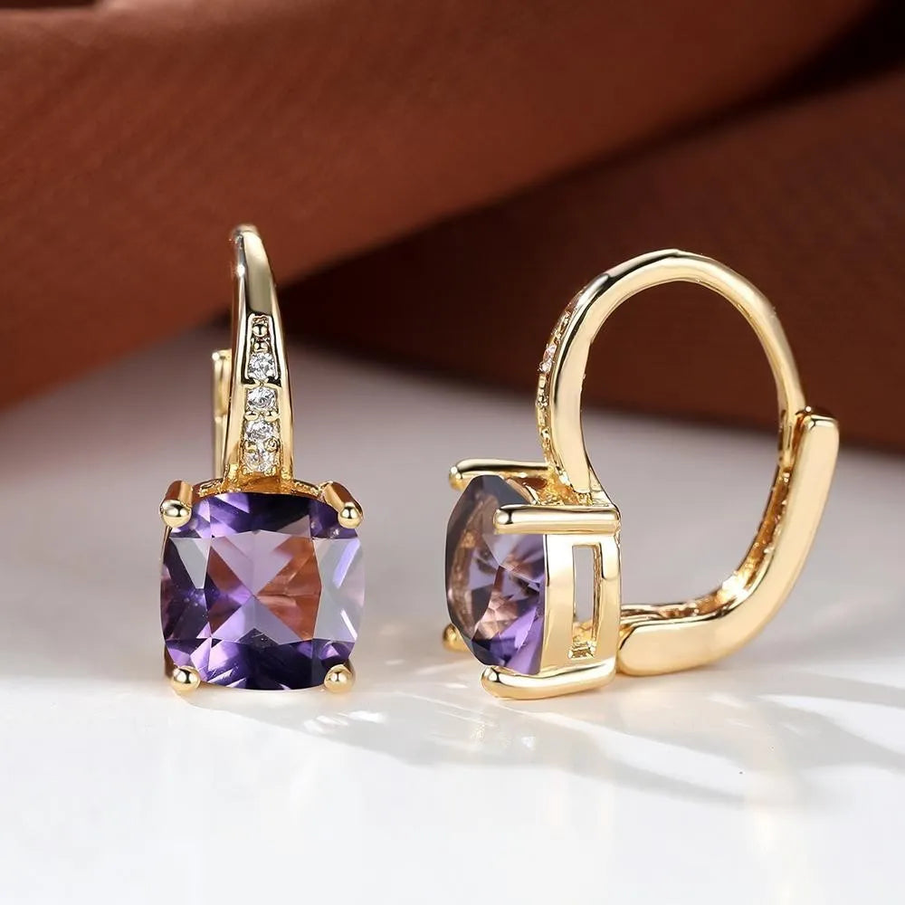 Geometric copper ear hook with round element and inlaid square zircon stone, shown in a golden colour.