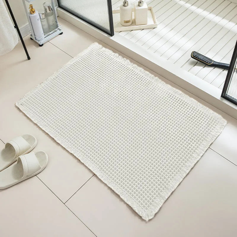 Square checkered polyester bathroom carpet on a tiled floor in a light grey colour.