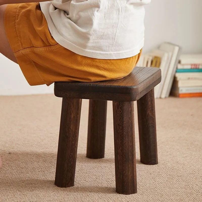 Solid wood household changing stool with a distressed finish for shoes in a living room.