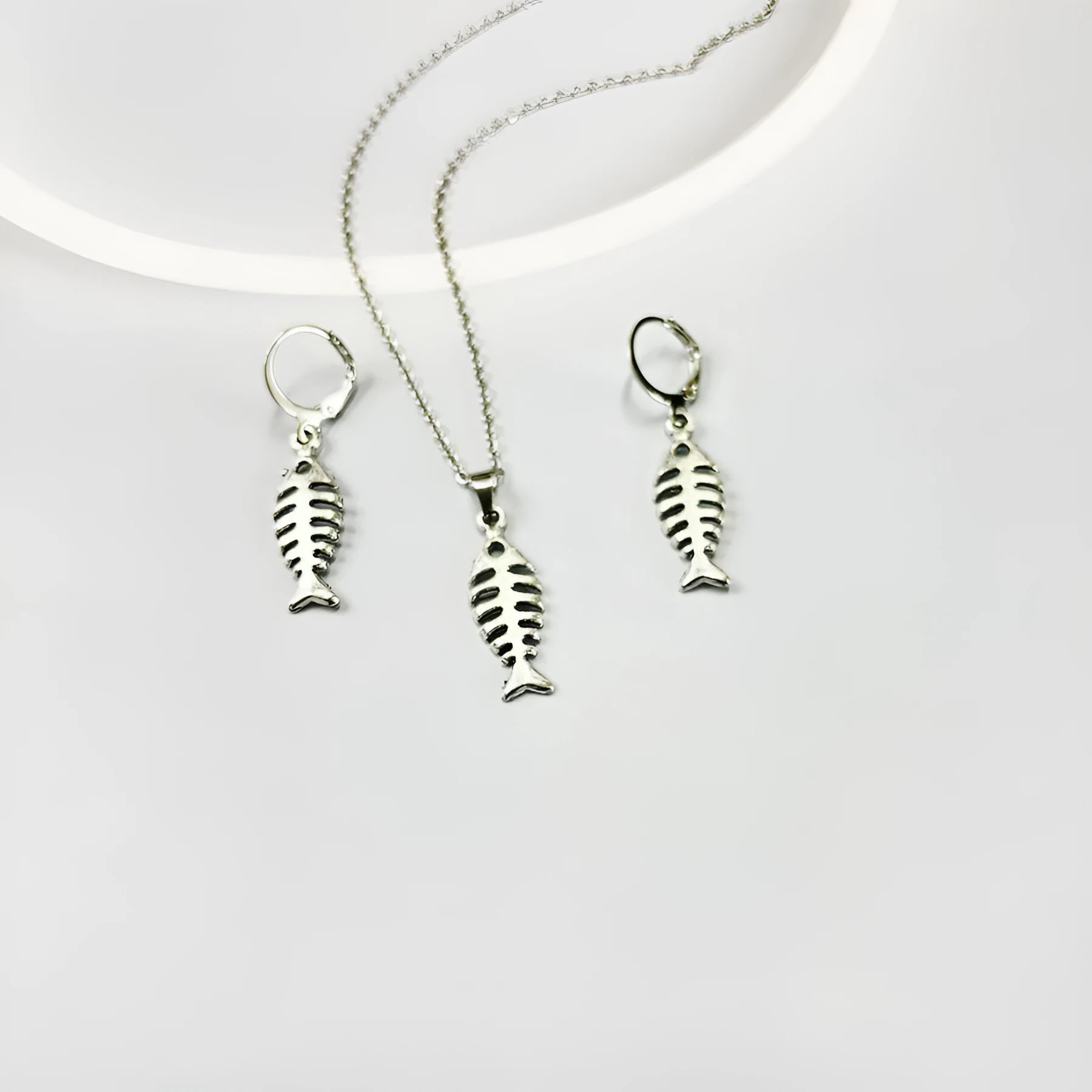 Silver-colour fishbone pendant necklace with O-chain and matching earrings on grey background