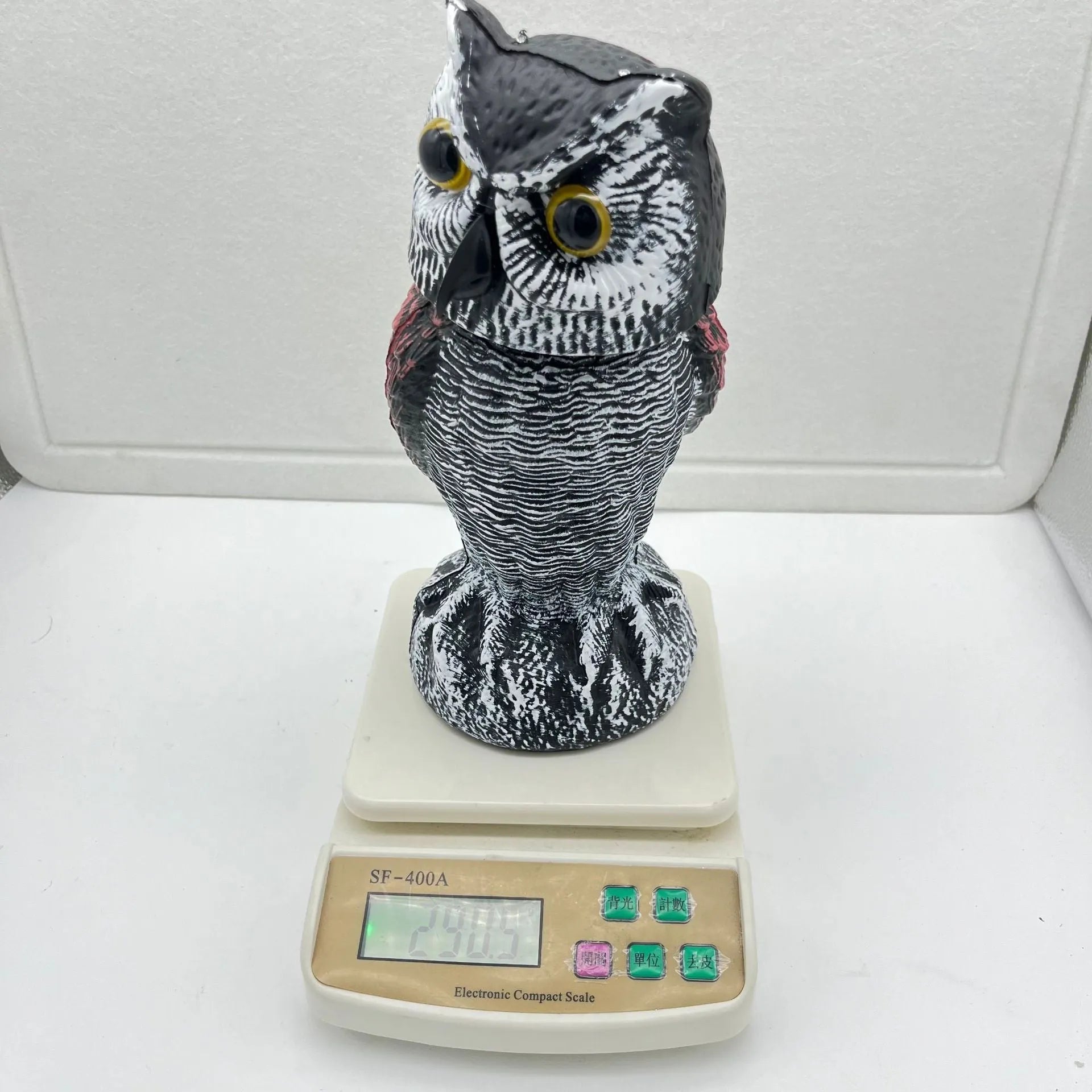 Artificial owl bird deterrent ornament with moving head in outdoor setting