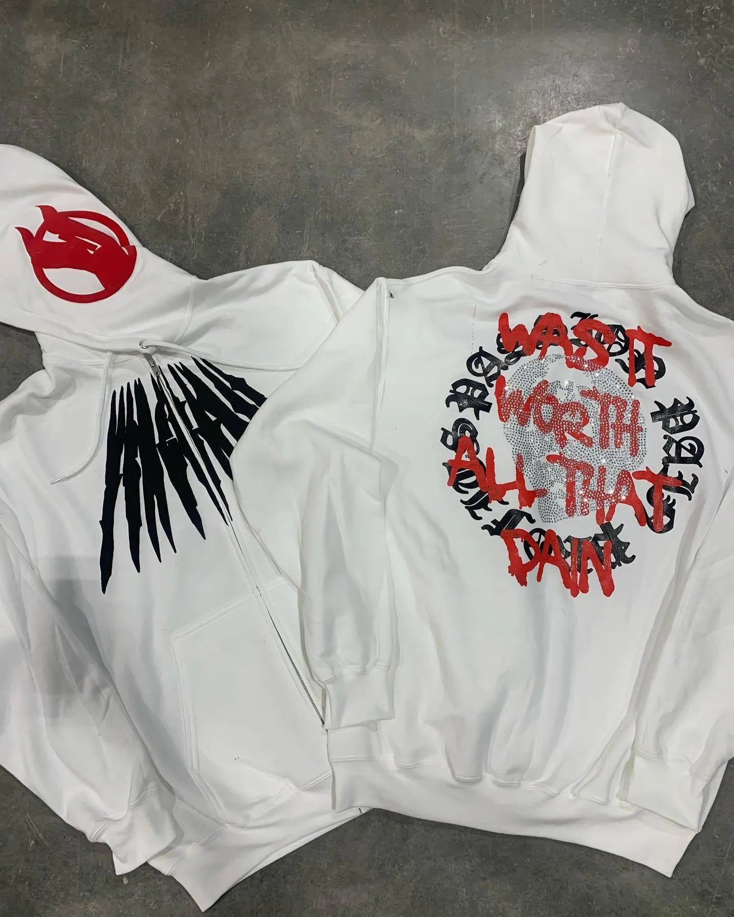 Black loose hooded sweatshirt with white printed skull and rhinestone design, showing cardigan style and long sleeves.