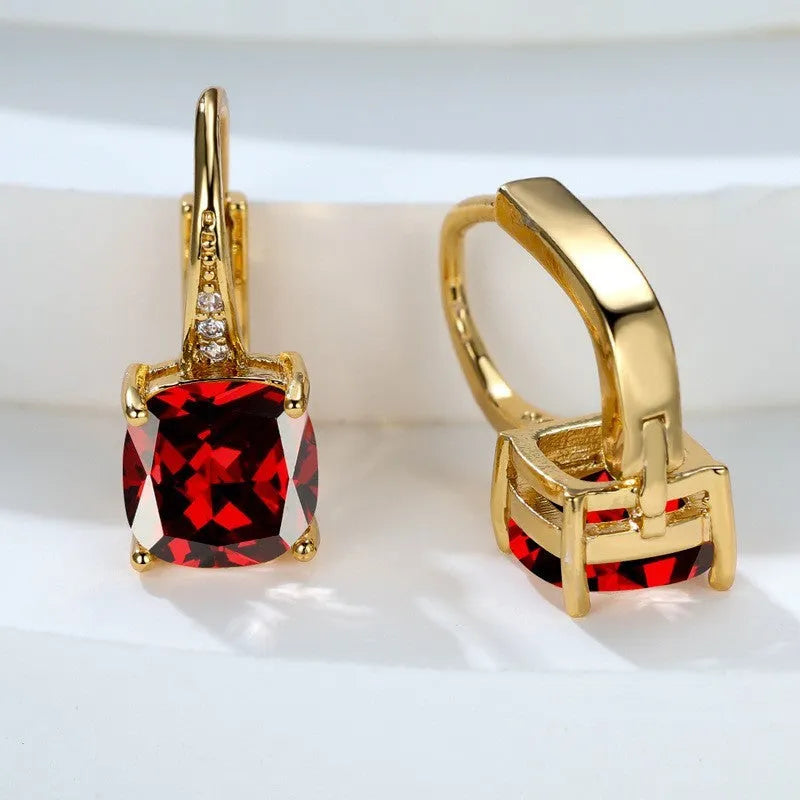 Geometric copper ear hook with round element and inlaid square zircon stone, shown in a golden colour.
