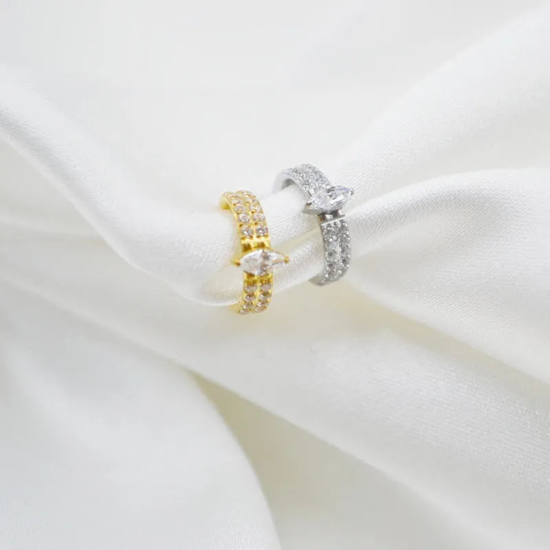 Close-up of a silver heart shaped titanium steel earring with a small zircon stone.