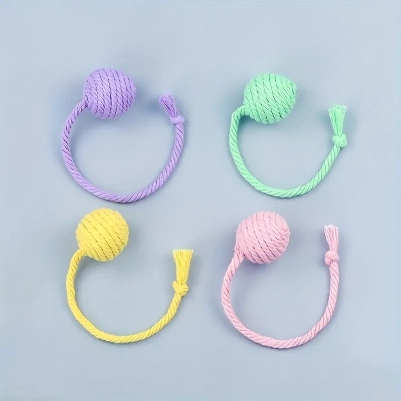 Green cat toy ball with a rope handle looped through it, shown next to a smaller pink version.