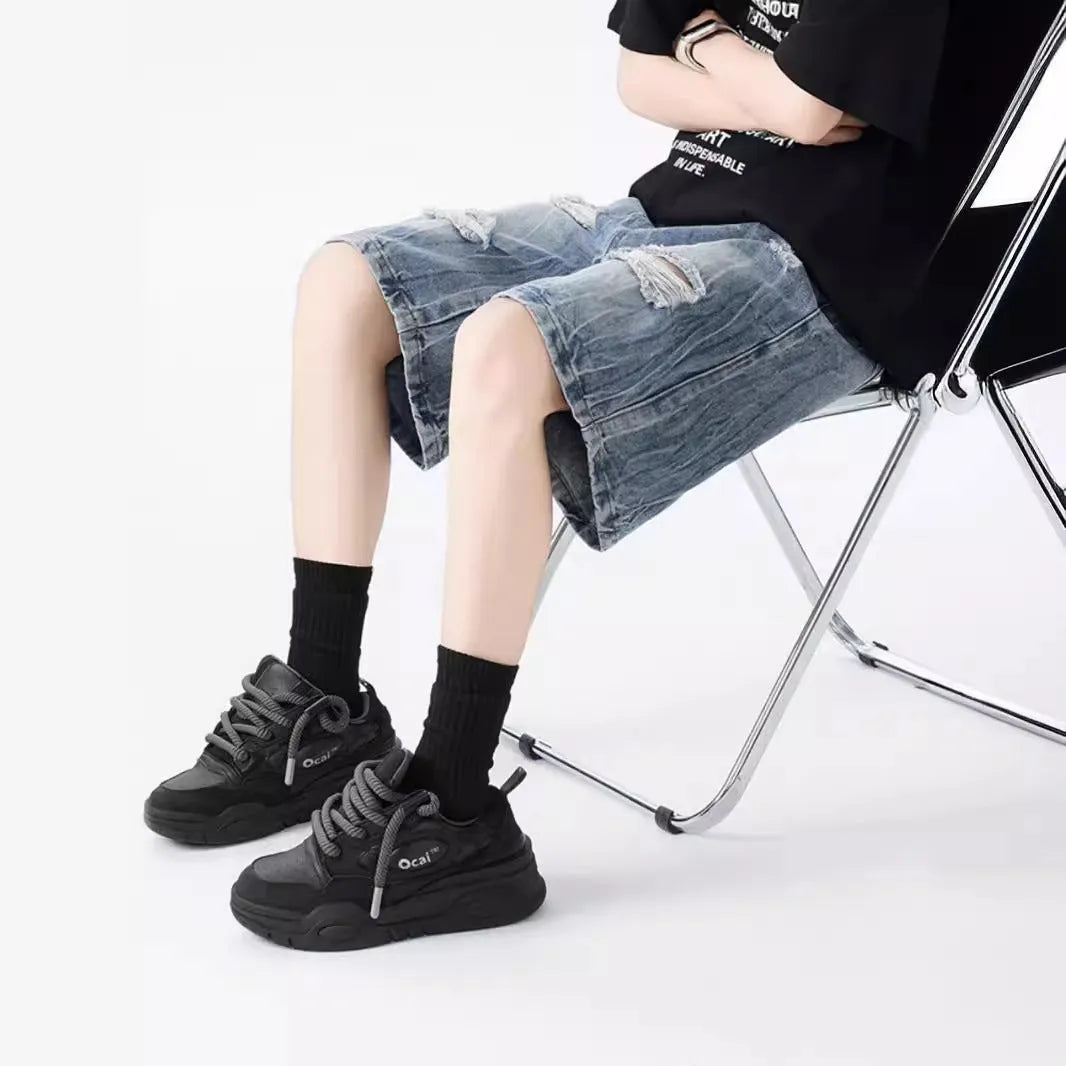 Model wearing loose-fit washed denim shorts with ripped details in blue.