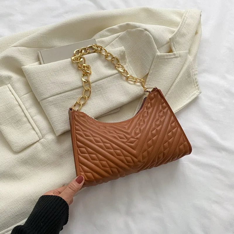 Brown pleated chain baguette women's shoulder bag with adjustable strap on a mannequin.