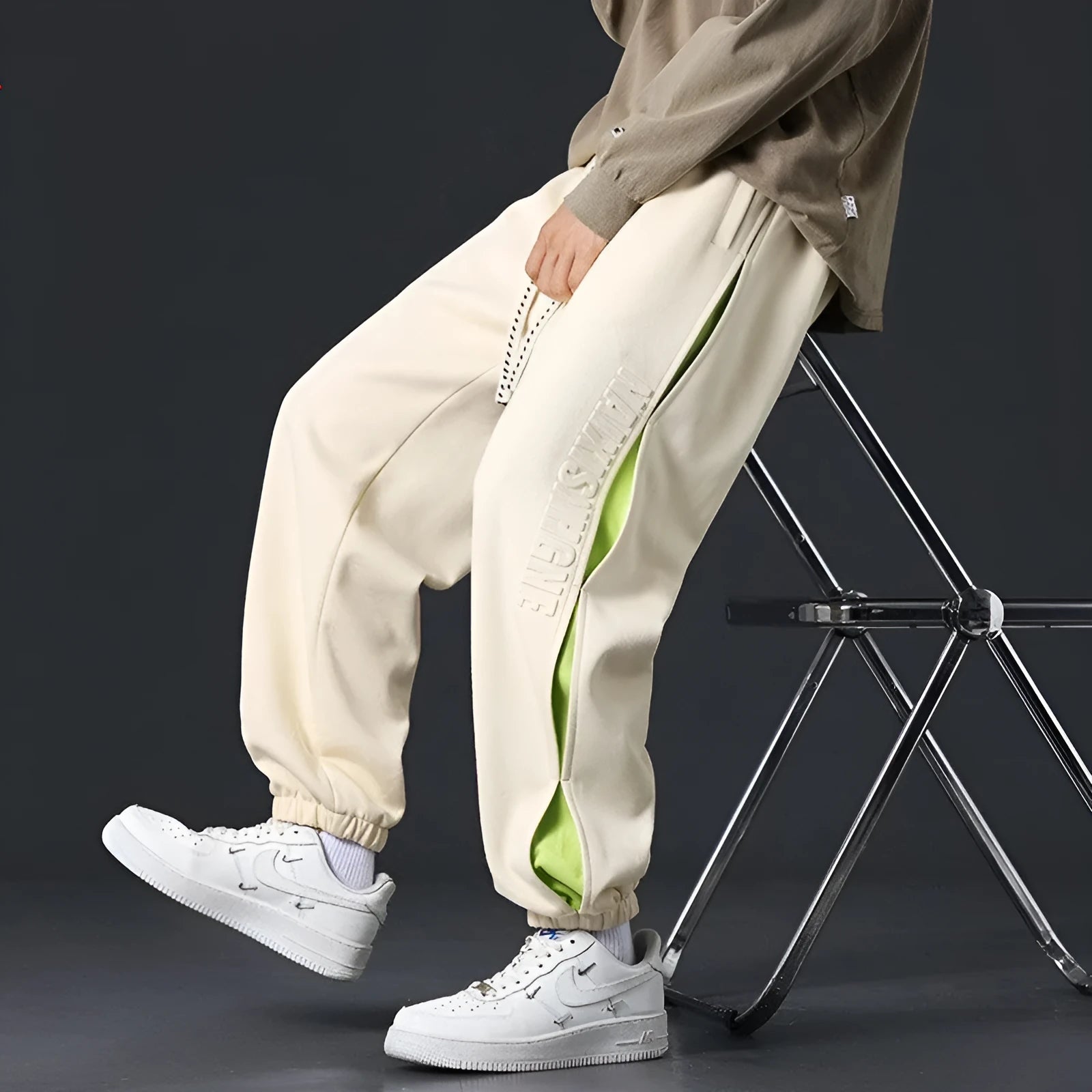 Man wearing grey green loose-fit cotton trousers with elastic ankle bands and visible stitch detailing.