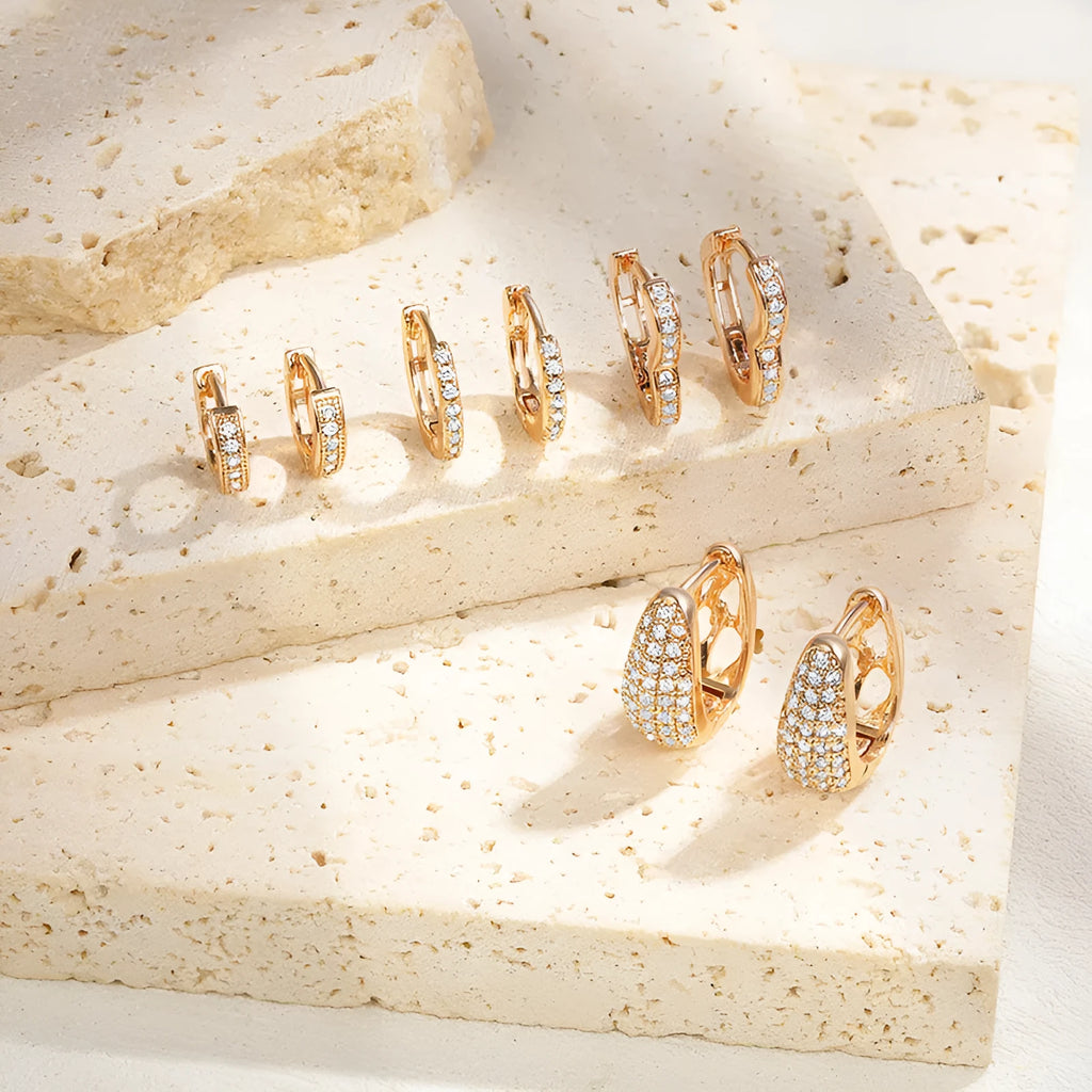 A pair of heart-shaped clip earrings with a single zircon stone in electroplated brass gold.