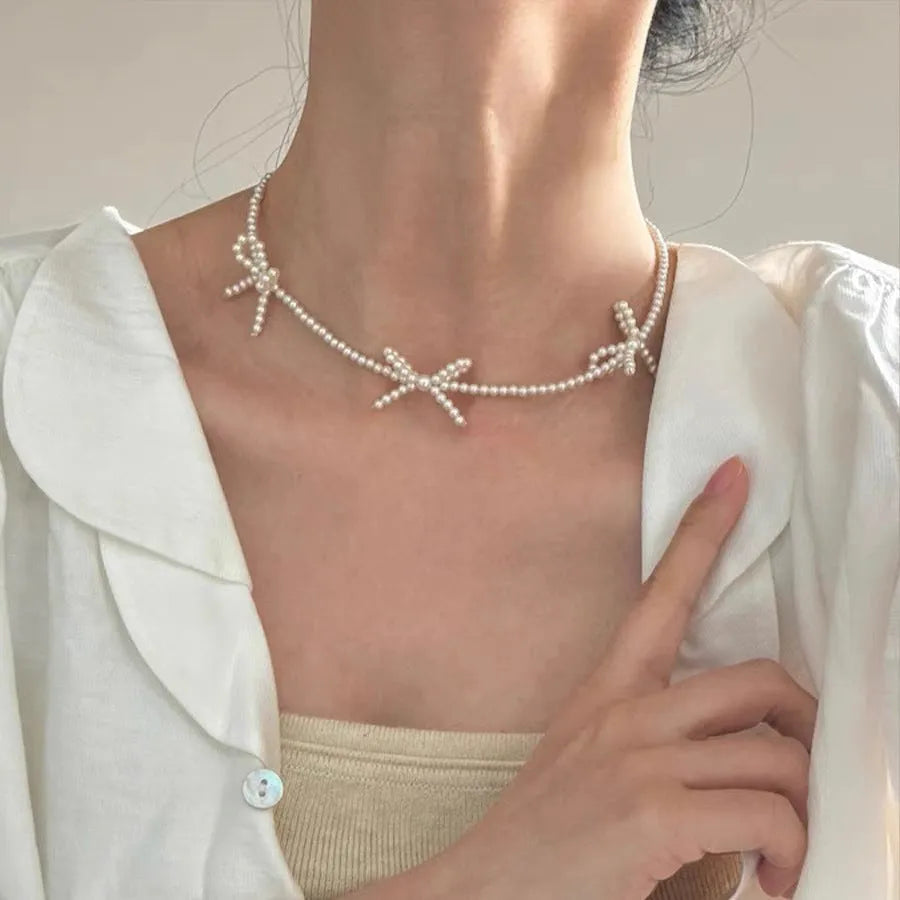 White imitation pearl necklace for women with an adjustable chain and a geometric sweet bow charm.