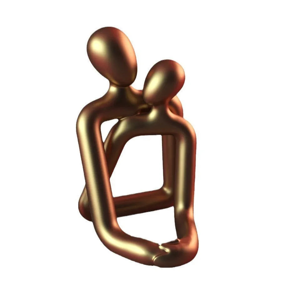 Modern couple resin statue in gold finish on a wooden desk.